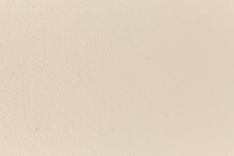 Eggshell-colored and subtly textured construction-style cardstock paper viewed in close detail. 