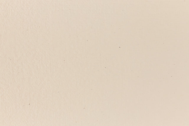 Eggshell-colored and subtly textured construction-style cardstock paper viewed in close detail. 